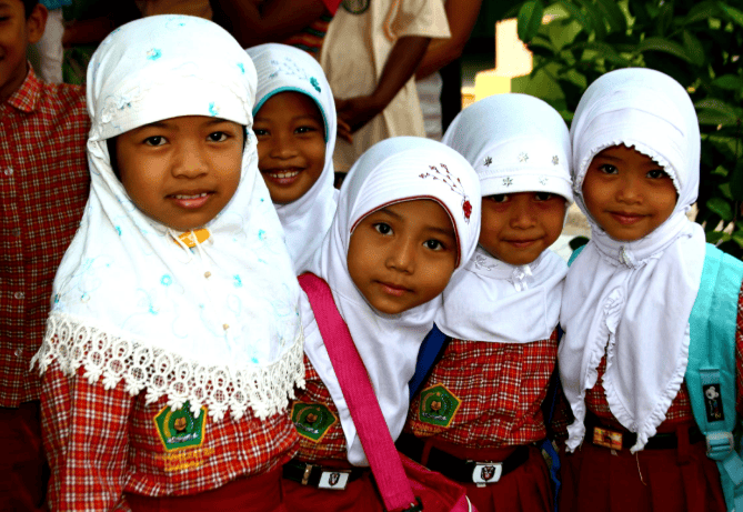 Group of Indonesian schoolgirls wearing white hijabs and red uniforms.